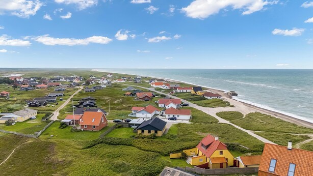 Een woongebied aan de kust met huizen, een strand en een heldere lucht.