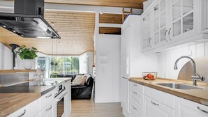 Eine moderne Küche mit weißen Schränken, einer Holz Arbeitsplatte und einem Edelstahlspülbecken.
