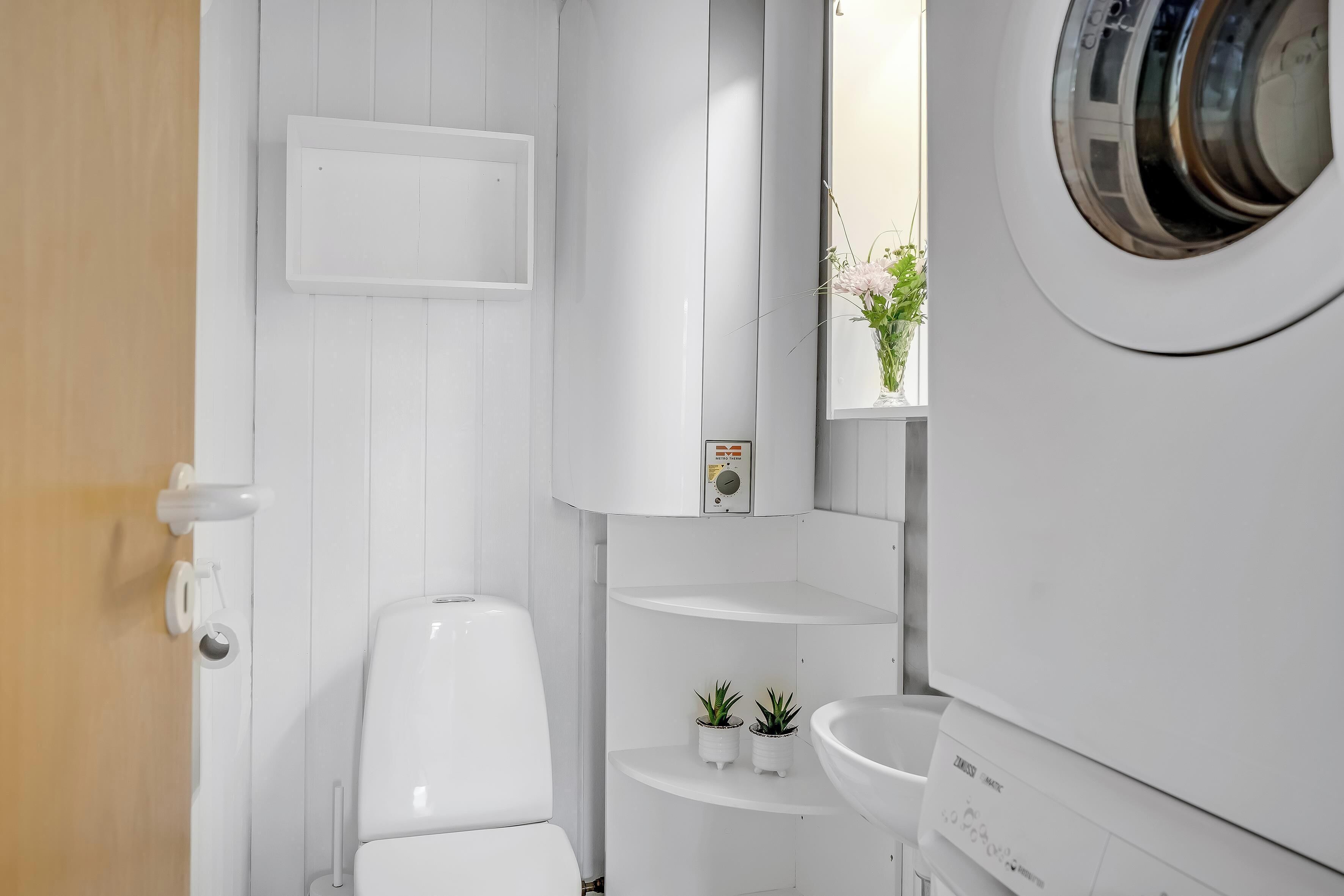 A compact, modern bathroom with a toilet, a washing machine, and a sink.