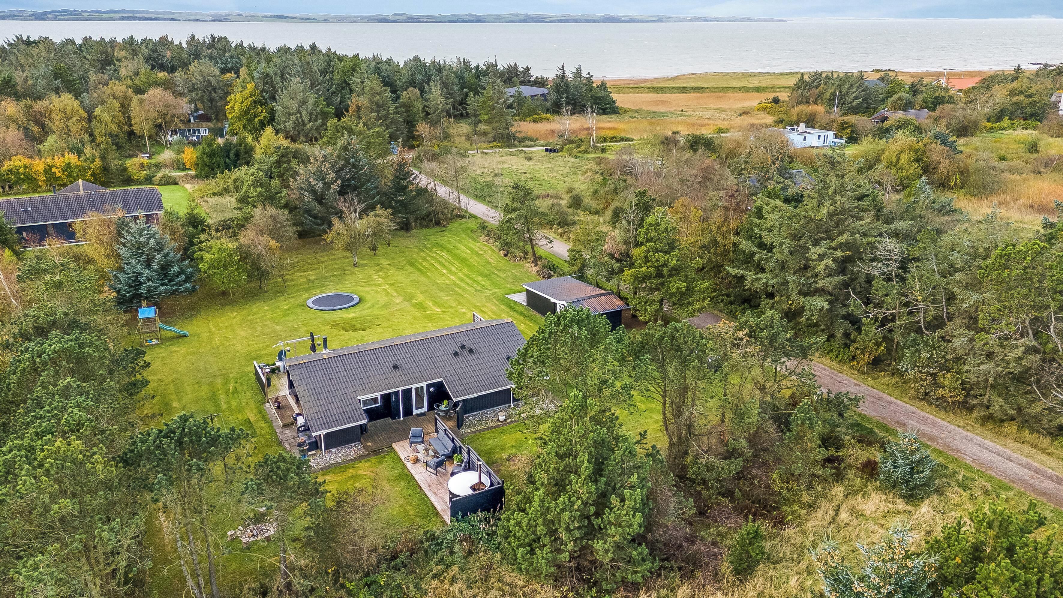 Une propriété résidentielle dotée d’une grande pelouse, d’une piscine et offrant une vue sur la mer.