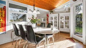 Eine moderne Küche mit Holzboden, weißen Schränken und einer Essecke mit schwarzen Stühlen und einem weißen Tisch.