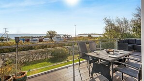 A deck with outdoor furniture, a view of boats on the water, and a clear sky.