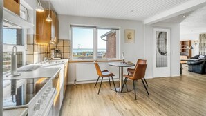 A modern kitchen with a large window, wooden cabinets, and a dining area with two chairs.