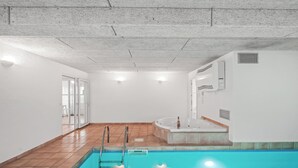 Ein Pool mit Whirlpool, eine Glastür, die nach draußen führt, und ein Fliesenboden.