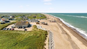 Luftaufnahme einer Küstenlandschaft mit Häusern, einem Strand und einem Boot.