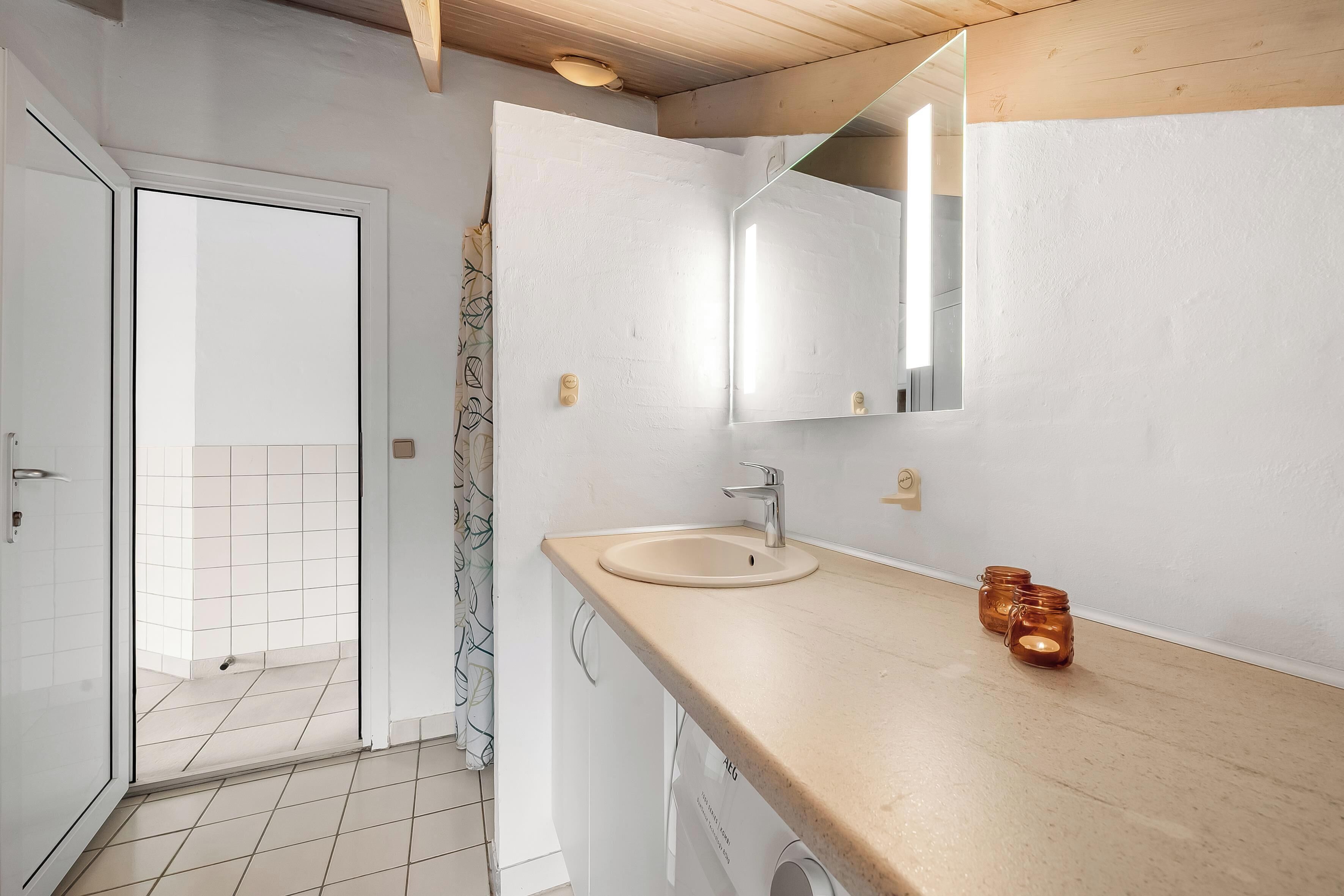 Un baño moderno con un tocador de madera, un lavabo blanco y un espejo.