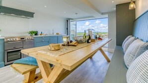 Eine moderne Küche mit einem Holztisch, der zum Essen gedeckt ist, einem Einbauofen und einem großen Fenster mit Blick auf die Landschaft.