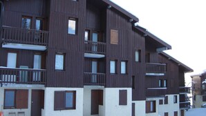 Un edificio de madera de varios pisos con balcones y ventanas, rodeado de nieve.