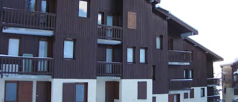 Un edificio de madera de varios pisos con balcones y ventanas, rodeado de nieve.