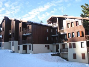 A multi-story hotel with wooden exterior walls, balconies, and a snowy ground.