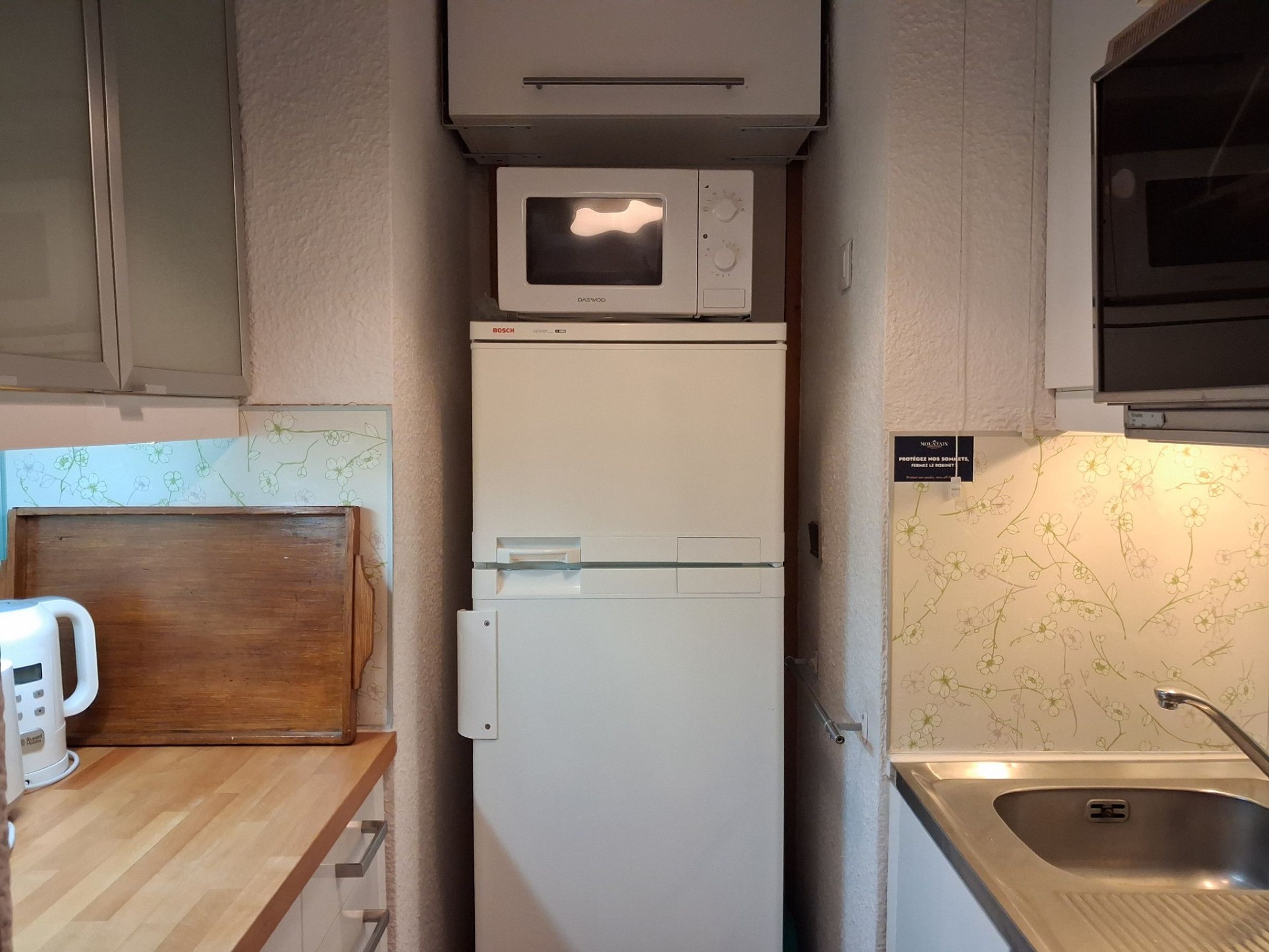 Eine kleine Küche mit Mikrowelle, Kühlschrank und Spüle.