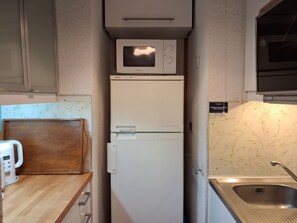 Una cocina compacta con microondas, refrigerador y pileta.