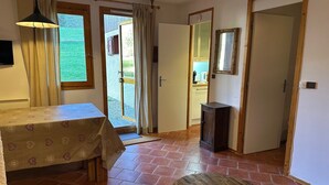 Una habitación con una mesa, un banco, un espejo y una puerta que da a una cocina.
