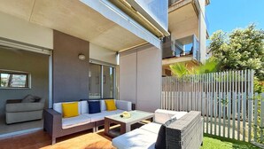Un balcon avec un canapé, une petite table et une chaise en osier.