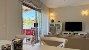 Un salon comprenant un canapé, un téléviseur et un coin repas avec une table et des chaises.