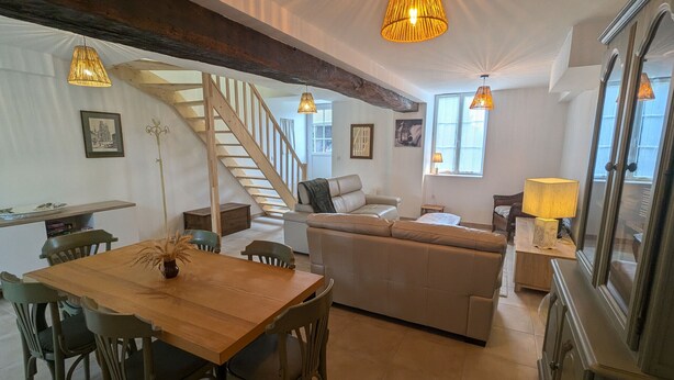Un vaste espace de vie comprenant une table à manger en bois, un canapé et un escalier menant à un niveau supérieur.
