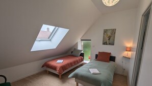 A small, modern bedroom with two single beds, a skylight, a painting, and a bedside lamp. - Gîte 1 Les Ratys: charm, tranquility and comfort near Orleans (Chaingy)