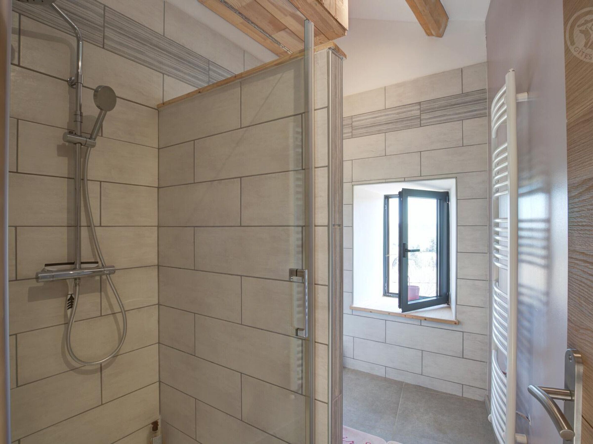 Ein Badezimmer mit Dusche, Fenster und Heizkörper.