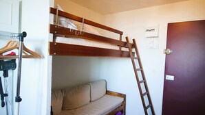 A bunk bed with a ladder, a sofa, and a door.