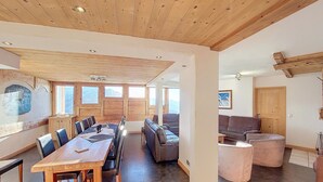 Un'ampia stanza con soffitto in legno, un grande tavolo da pranzo e un divano.