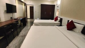 A hotel room with a bed, a desk, a chair, a TV, and a wardrobe. - Hotel corporate suites (Bengaluru)