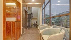 A hallway with a staircase, a wooden wall, and a seating area with chairs. - Hotel corporate suites (Bengaluru)