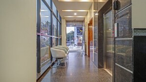 A hallway with a glass wall, a reception desk, and a phone on the wall. - Hotel corporate suites (Bengaluru)