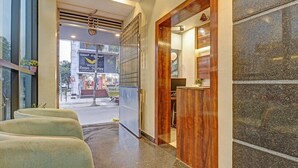 A hotel lobby with a reception desk, a waiting area with chairs, and a view of the street outside. - Hotel corporate suites (Bengaluru)