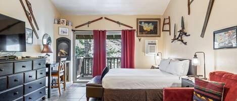 A bedroom with a bed, a red sofa, a TV, a dresser, and a balcony with red curtains.