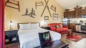 A bedroom with a large bed, a red sofa, and a kitchen area with modern appliances. - Cozy stay for 4: 5 Min Drive to Base,  Full Kitchen, Shared Hot Tub & Pool, Restaurants Nearby! (Park City)