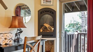 A cozy room with a fireplace, a dining table with a lamp, and a chair. - Cozy stay for 4: 5 Min Drive to Base,  Full Kitchen, Shared Hot Tub & Pool, Restaurants Nearby! (Park City)