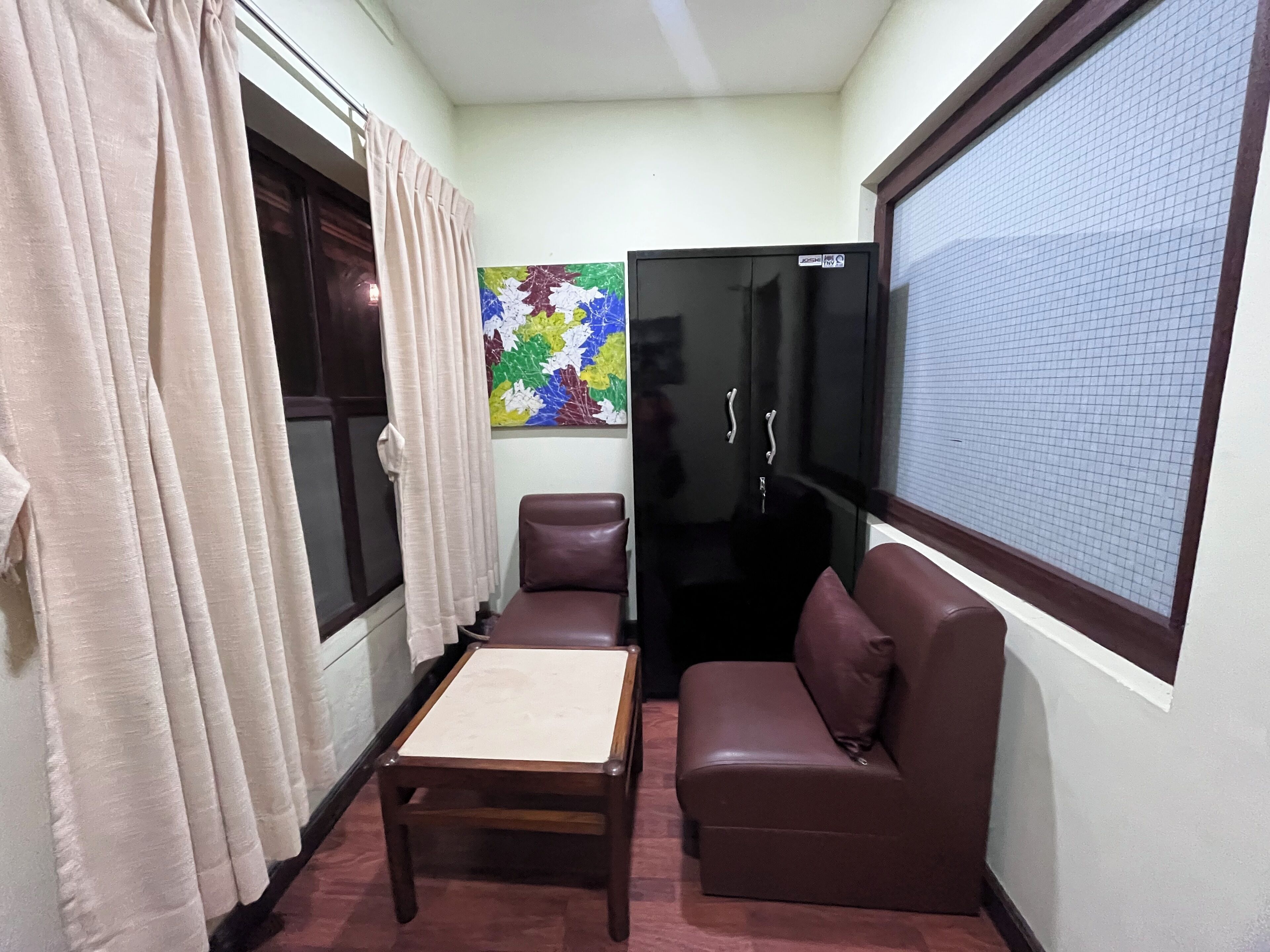 Una habitación pequeña y acogedora con sofá, una mesita y un refrigerador.