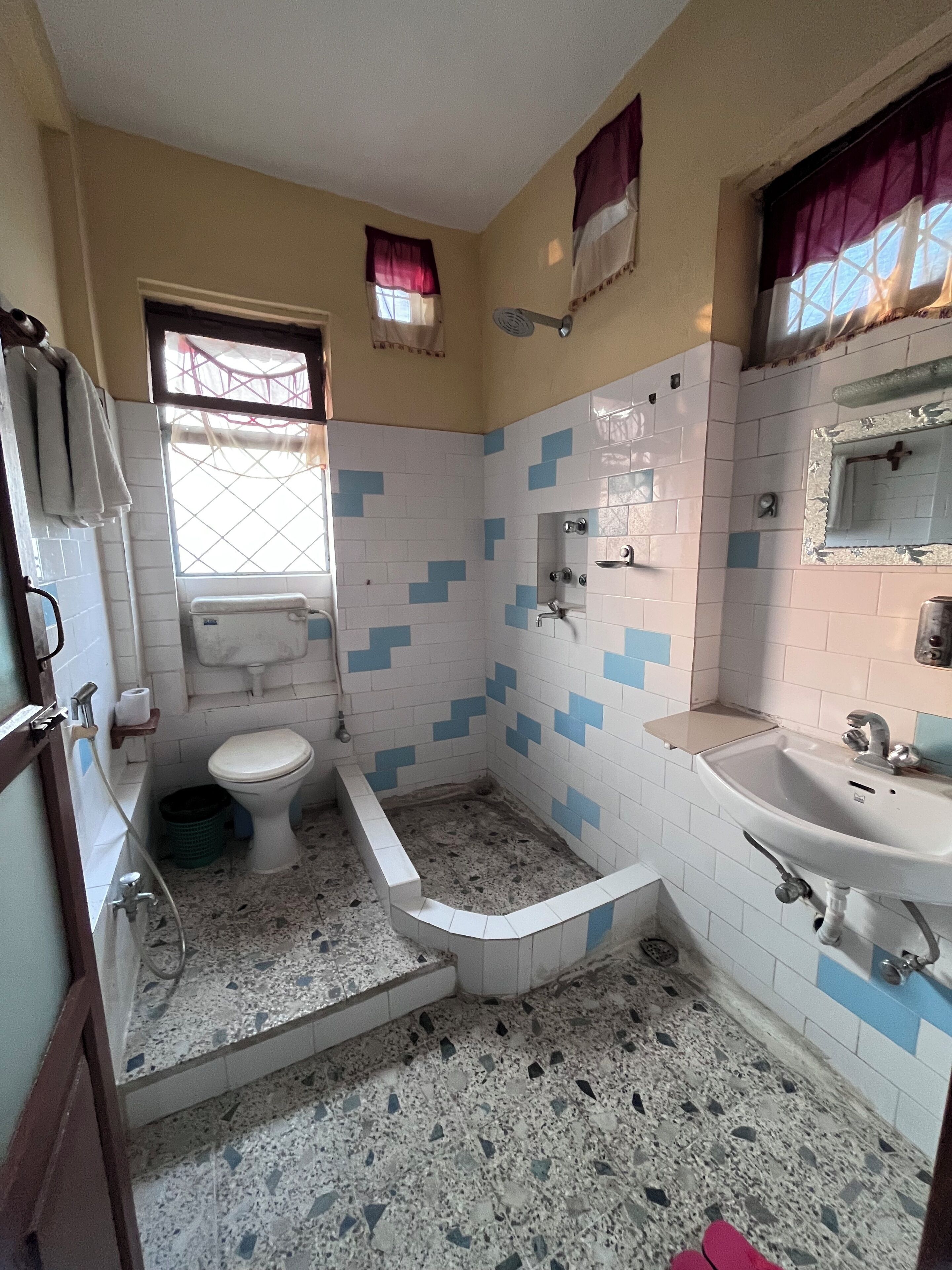 A bathroom with a toilet, sink, and shower. The walls are tiled with a blue and white pattern.
