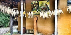 Un edificio rústico con un mural en la pared, calabazas secándose en un tendedero y un poste de madera en primer plano.