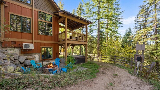 Eine Holzhütte mit Terrasse, Sitzgelegenheiten im Freien und einer Feuerstelle.