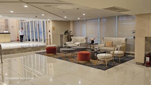 A modern lobby with a seating area, a reception desk, and a fire extinguisher. - Makati Bliss Apartment - Cozy Urban Retreat (Makati)
