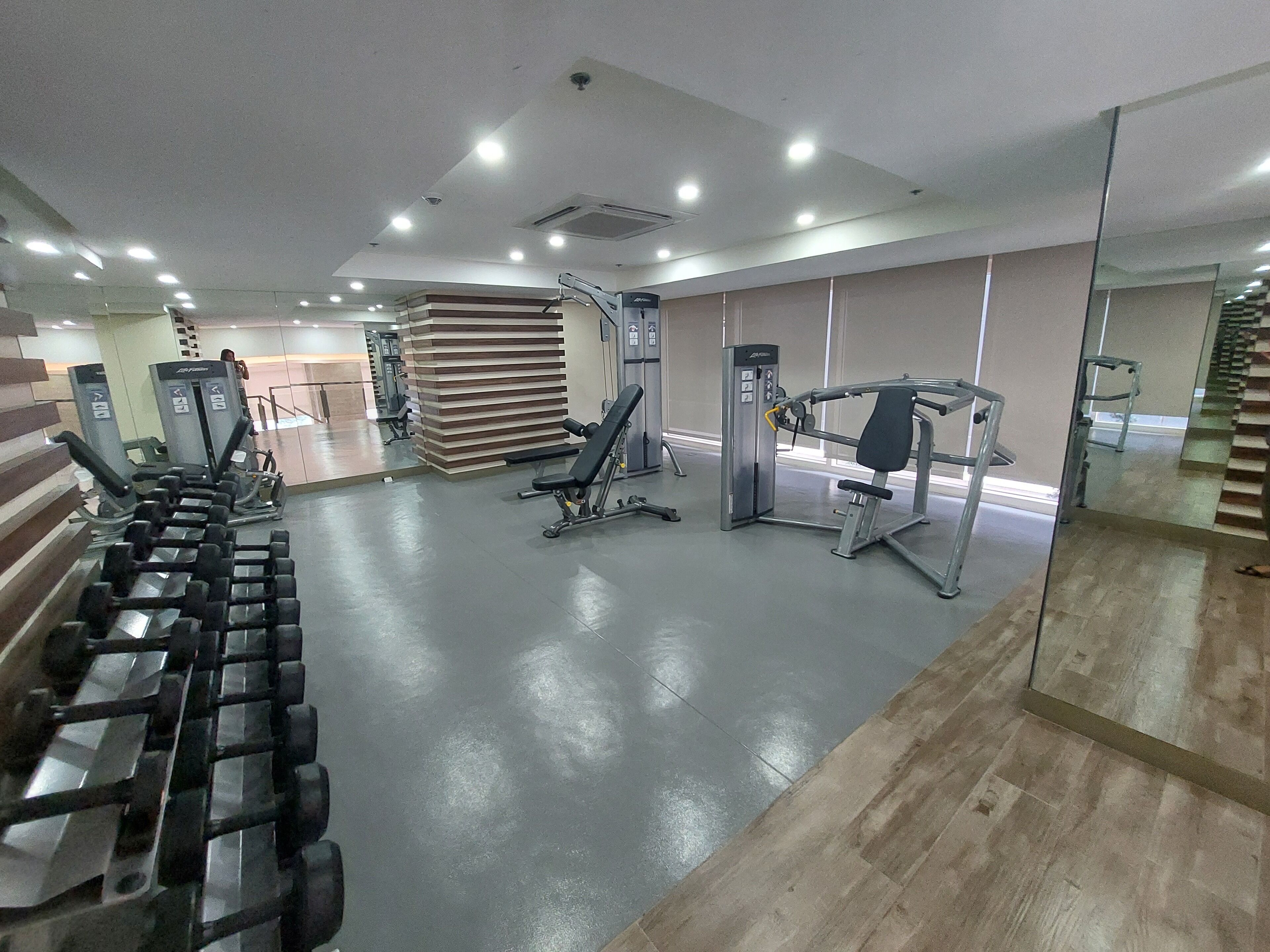 Un gimnasio con diverso equipo de ejercicio, incluyendo mancuernas, una prensa de banca y una máquina de poleas.