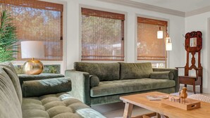 A living room with a green sofa, a wooden coffee table, and a lamp.