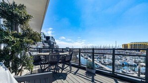 A wooden deck with outdoor seating, overlooking a marina with boats and a clear blue sky. - Apartment in Sint-annaland With Beach Access (Sint-Annaland)