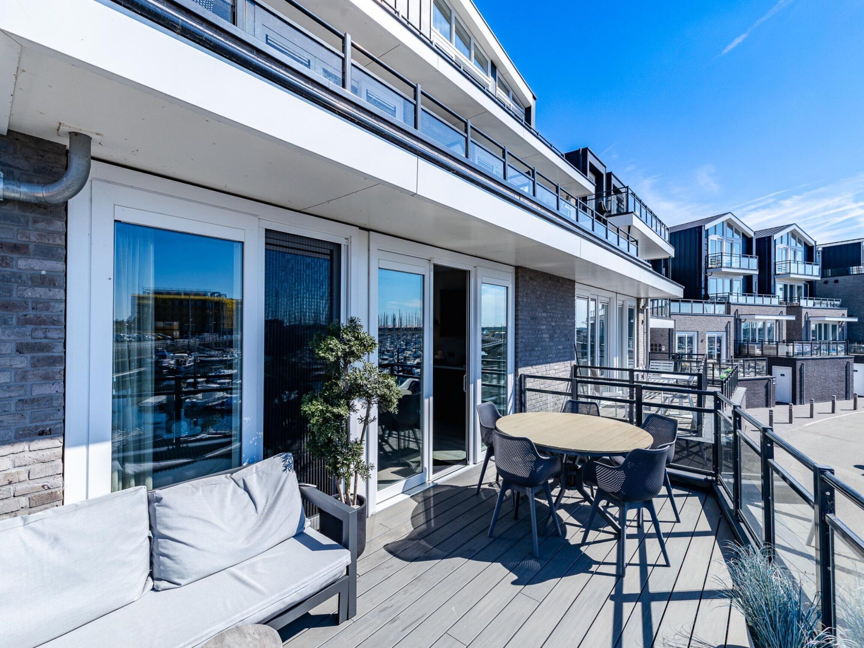 A modern building with a rooftop deck featuring outdoor seating and a view of the cityscape.