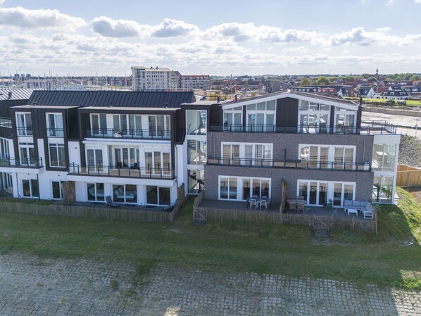 Un edificio residencial moderno de varios pisos con balcones, ventanas amplias y techo plano.