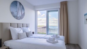 Habitación de hotel con una cama grande, vista al mar y un cuadro en la pared.
