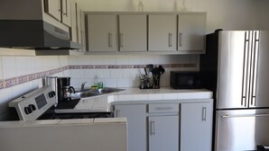 A kitchen with white cabinets, a stainless steel refrigerator, a microwave, and a stove. - Marina House  (Arroyo)