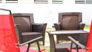 Two wicker chairs and a small table outside a building with white walls and horizontal blinds. - Marina House  (Arroyo)