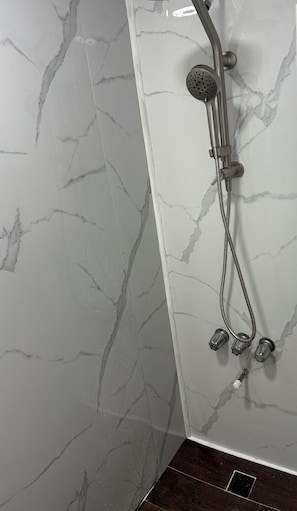 A shower with a handheld showerhead, a handheld shower attachment, and a wall-mounted showerhead.