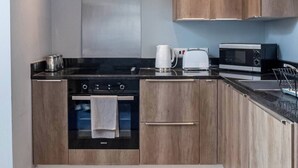 Une cuisine moderne avec des meubles en bois, un plan de travail noir, une cuisinière, un four à micro-ondes et une machine à café.