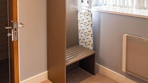 Un dressing accessible sans porte, avec un banc, des étagères et un sac suspendu.