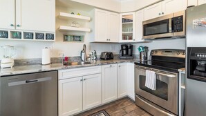Una cocina moderna con armarios blancos, electrodomésticos de acero inoxidable y encimera de granito.