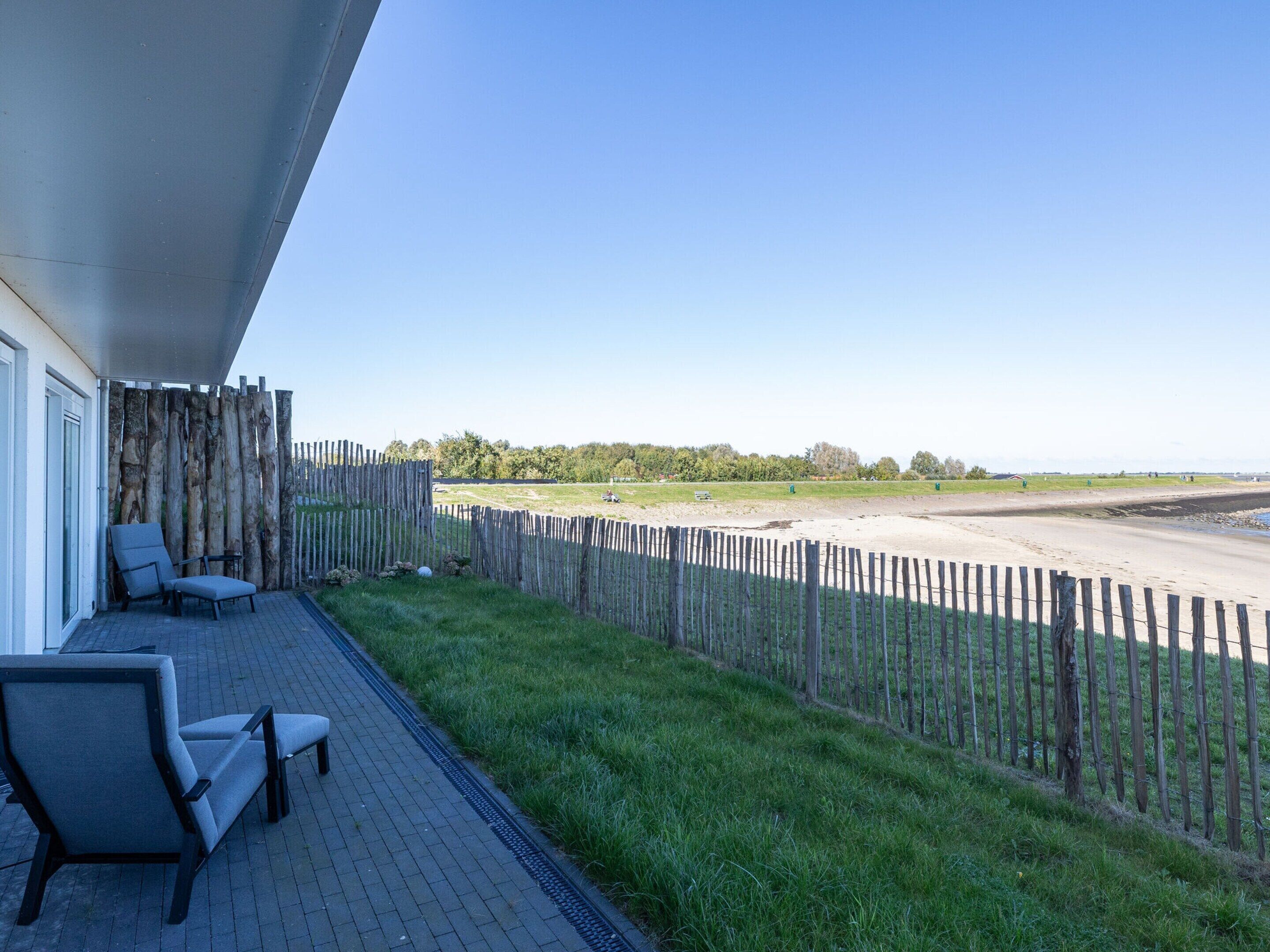 A balcony with a view of a beach and a grassy area.