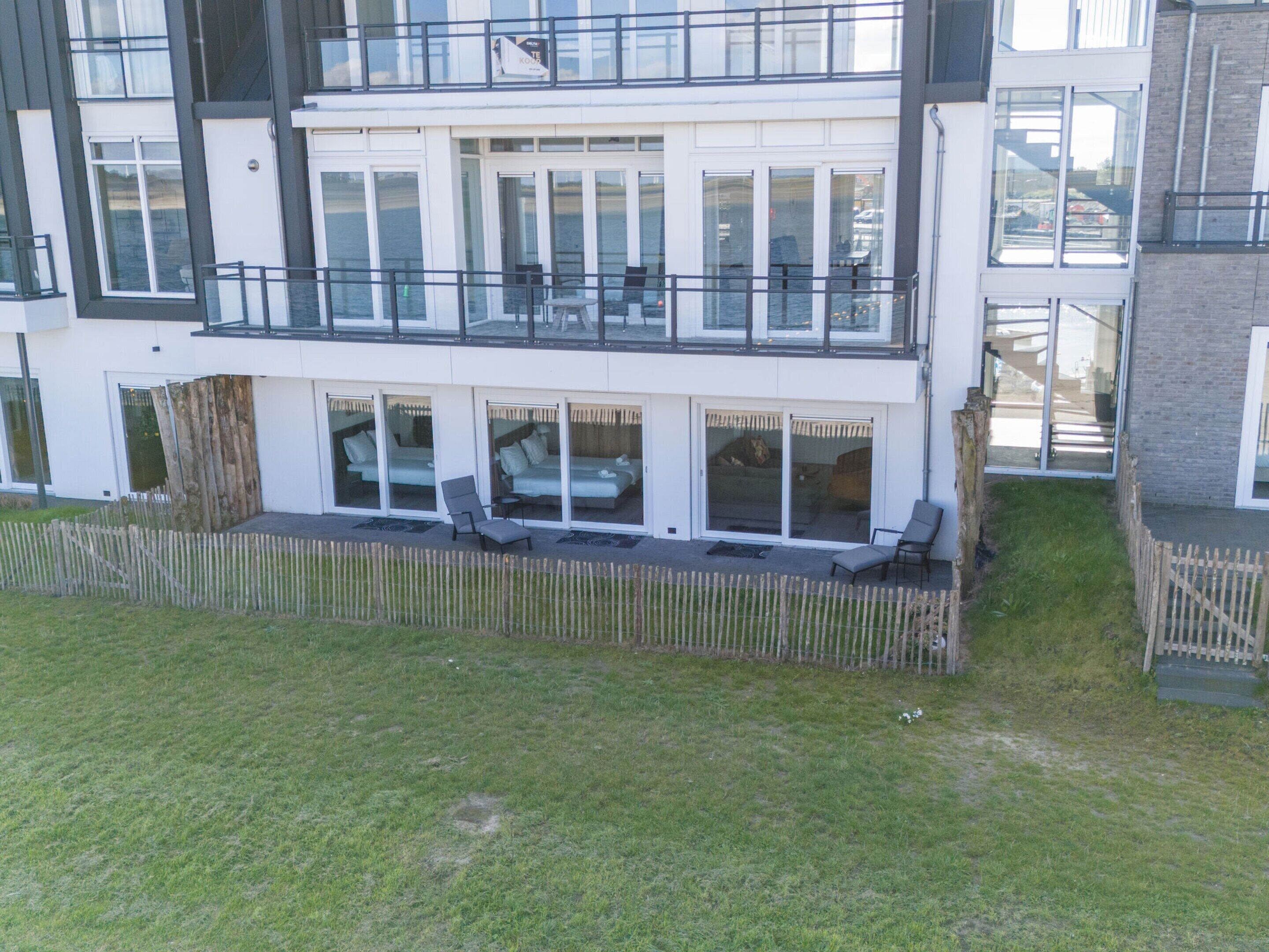 Un edificio moderno su due piani, con ampie finestre, un balcone e un'area esterna recintata.